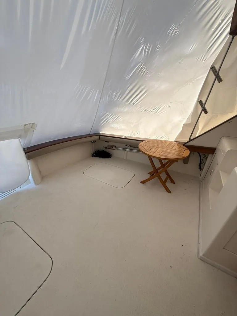 Slide: The Image of 1989 Post 43 Sport Fisherman boat interior with wooden table and white seating area. - 2