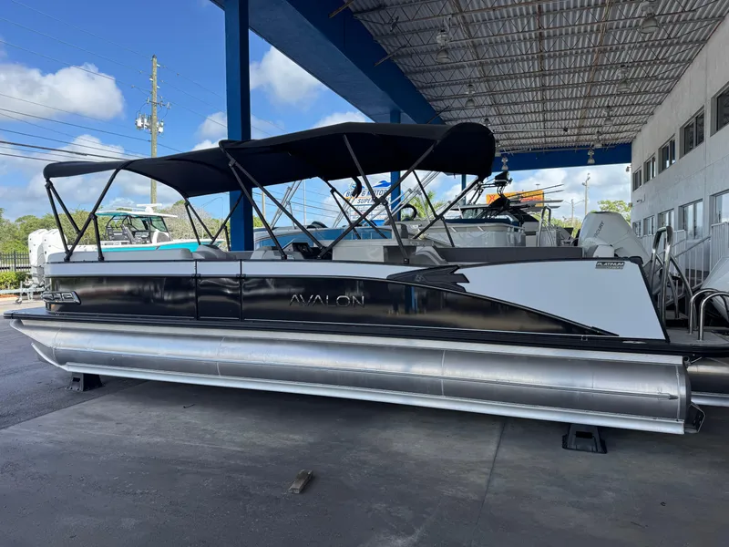 Slide: The Image of 2025 Avalon Catalina Entertainer 27' pontoon boat with black canopy, docked under shelter. - 3