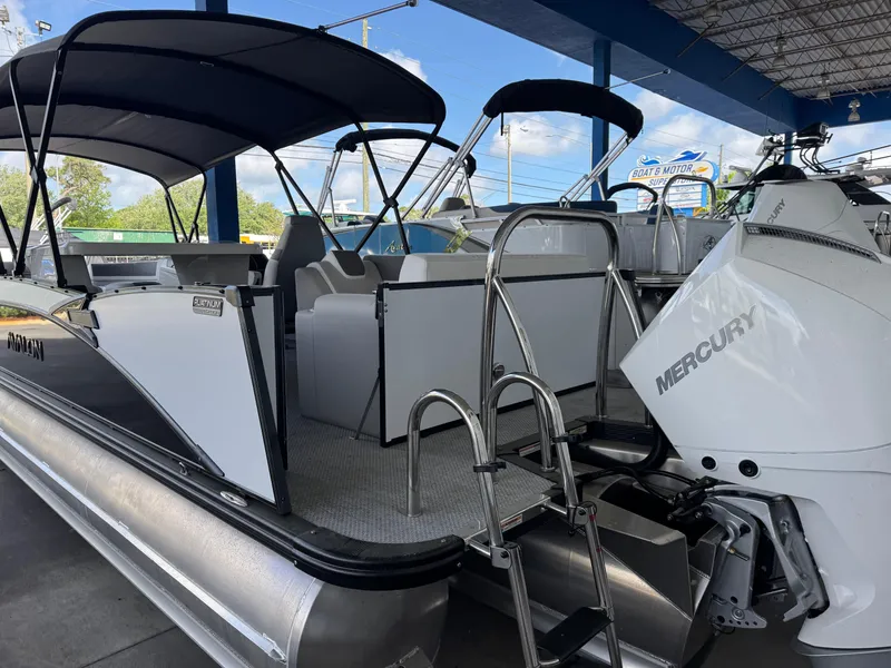 Slide: The Image of 2025 Avalon Catalina Entertainer 27' pontoon boat with Mercury engine, docked under shelter. - 4