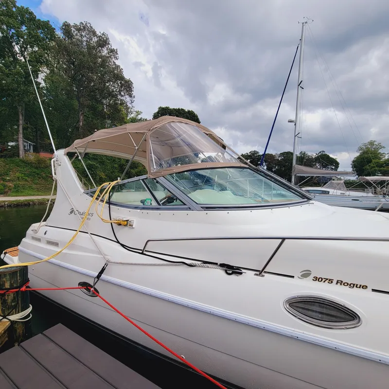 Slide: The Image of 1999 Cruisers Yachts 3075 Rogue docked, featuring sleek design and beige canopy. - 15