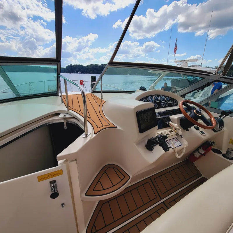 Slide: The Image of 1999 Cruisers Yachts 3075 Rogue cockpit with steering wheel, dashboard, and lake view. - 23