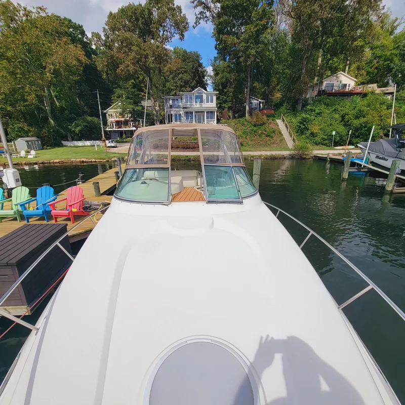 Slide: The Image of 1999 Cruisers Yachts 3075 Rogue docked by a scenic waterfront with colorful chairs. - 30