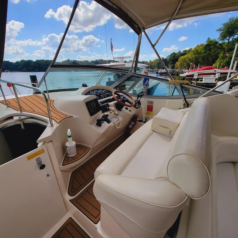 Slide: The Image of 1999 Cruisers Yachts 3075 Rogue cockpit with steering wheel, seating, and lake view. - 4