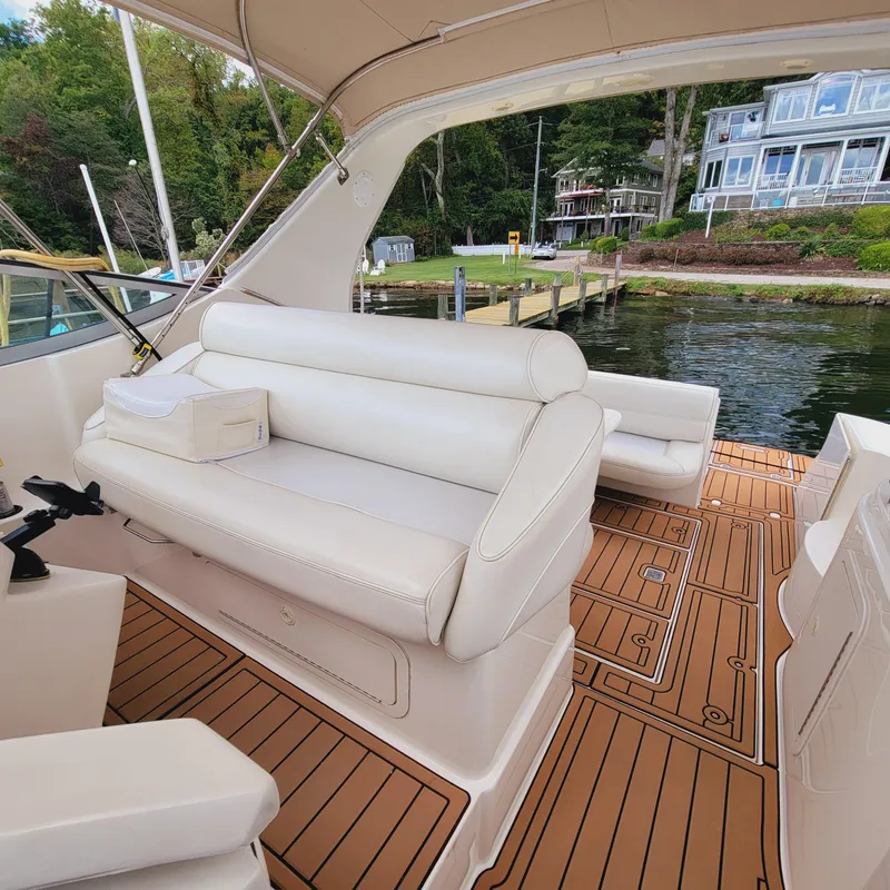 Slide: The Image of 1999 Cruisers Yachts 3075 Rogue interior with white seating and wooden deck, dockside view. - 49