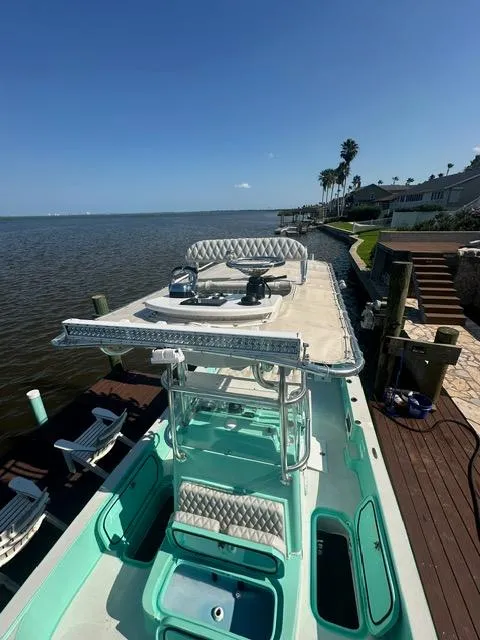 Slide: The Image of 2022 Shallow Sport 28 X3 boat docked by waterfront homes under clear blue sky. - 10