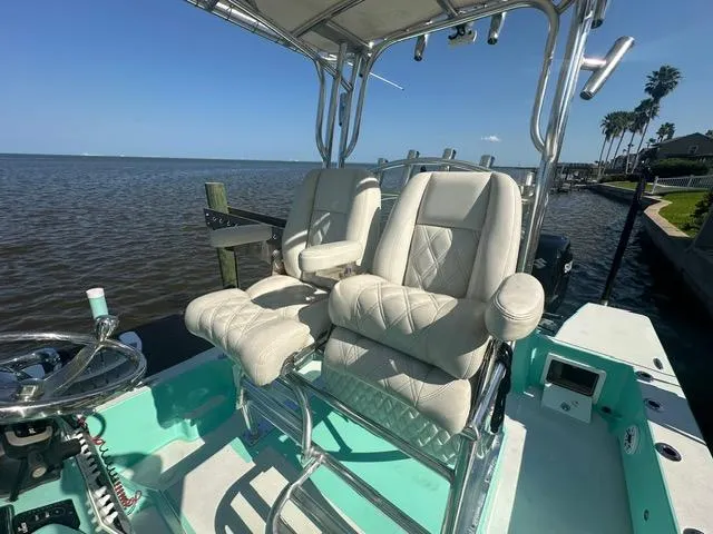 Slide: The Image of 2022 Shallow Sport 28 X3 boat with cushioned seats, docked by the water. - 11