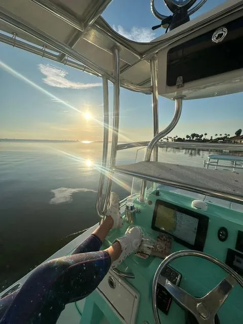 Slide: The Image of 2022 Shallow Sport 28 X3 boat at sunrise, calm waters, person relaxing. - 18