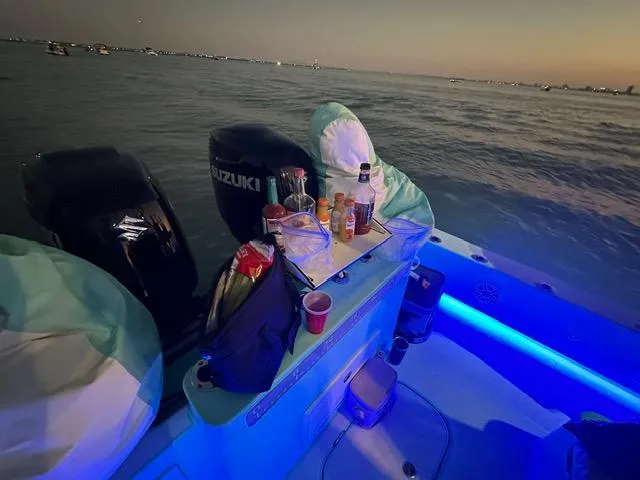 Slide: The Image of 2022 Shallow Sport 28 X3 boat with Suzuki engines, evening setup with drinks and snacks. - 19