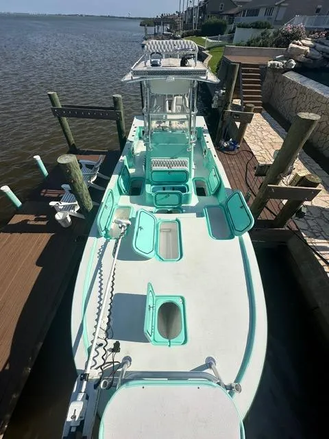 Slide: The Image of 2022 Shallow Sport 28 X3 boat docked, featuring open storage compartments and a central console. - 8