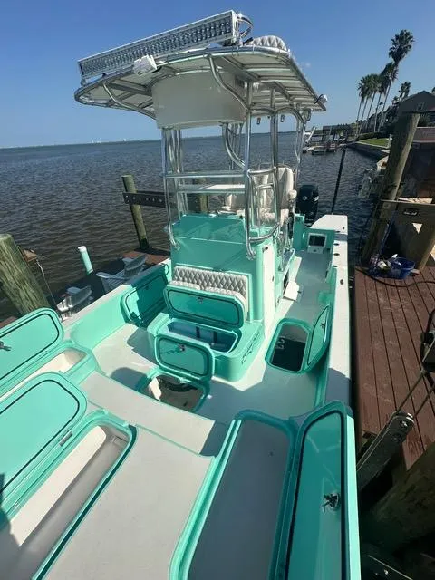 Slide: The Image of 2022 Shallow Sport 28 X3 boat docked, featuring open storage compartments and a central console. - 9