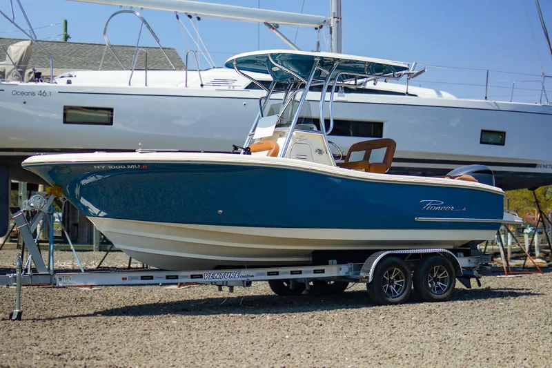 Slide: The Image of 2022 Pioneer 222 Islander boat on trailer, blue hull, parked outdoors. - 0