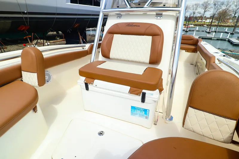 Slide: The Image of 2022 Pioneer 222 Islander boat interior with brown and white seating at a marina. - 3