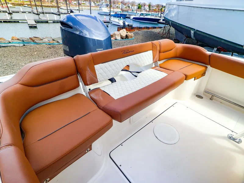 Slide: The Image of 2022 Pioneer 222 Islander boat with tan leather seating, docked at a marina. - 7