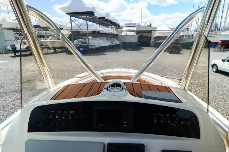 Slide: The Image of 2022 Pioneer 222 Islander boat dashboard with wood accents, parked in a marina. - 9