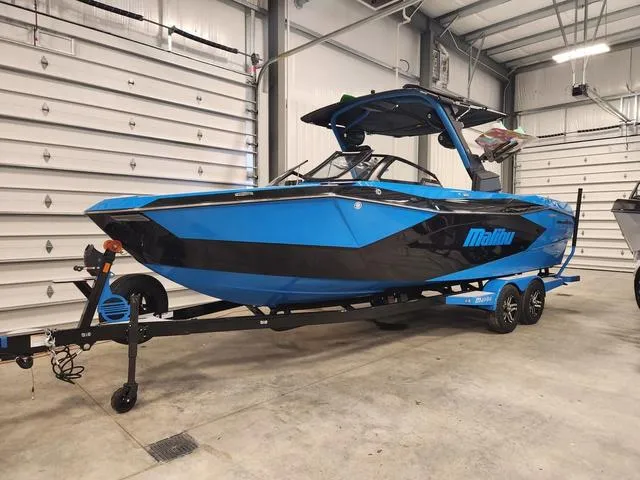 Slide: The Image of 2023 Malibu 26 LSV boat in a garage, featuring a sleek blue and black design. - 0