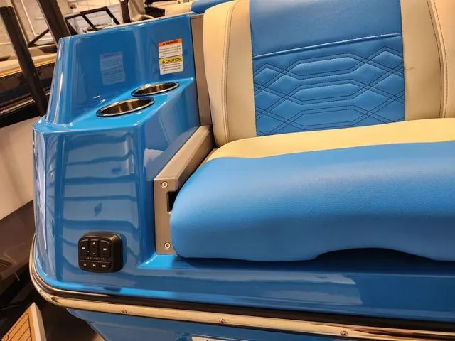 Slide: The Image of 2023 Malibu 26 LSV boat interior with blue and beige seating, cup holders, and control panel. - 11