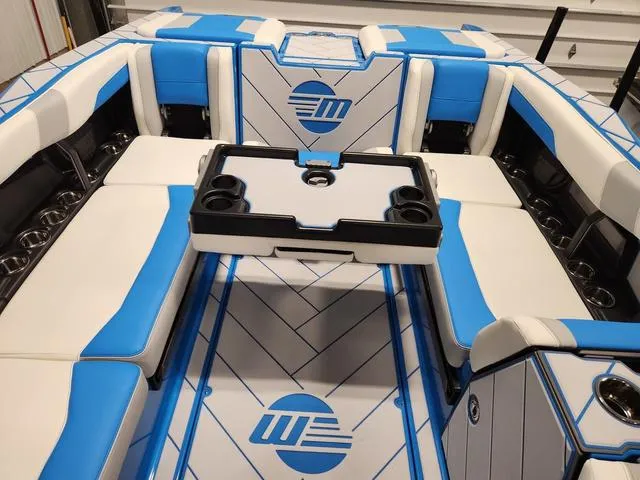 Slide: The Image of 2023 Malibu 26 LSV boat interior with blue and white seating and cup holders. - 17