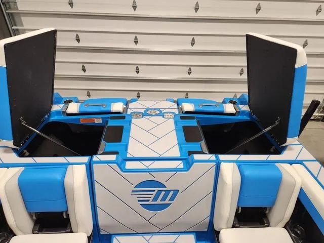 Slide: The Image of 2023 Malibu 26 LSV boat interior with blue and white seating and open storage compartments. - 22