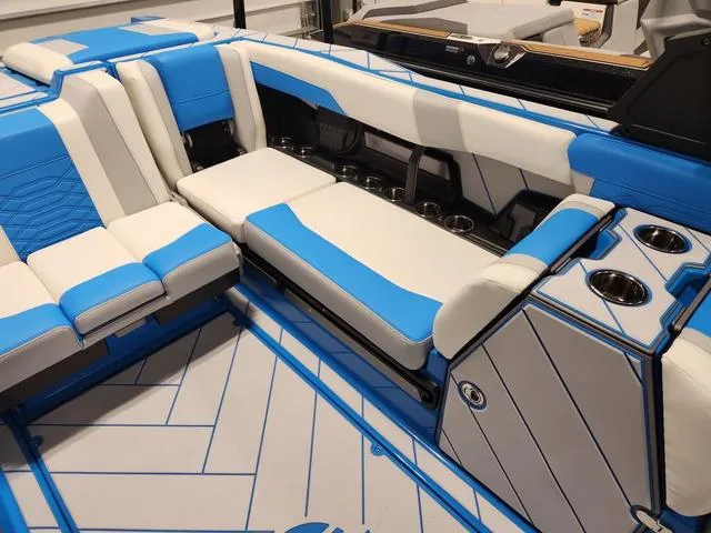 Slide: The Image of 2023 Malibu 26 LSV boat interior with blue and white seating and cup holders. - 27