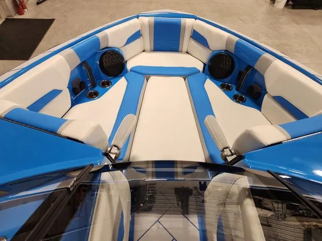 Slide: The Image of 2023 Malibu 26 LSV boat interior with blue and white seating, cup holders, and speakers. - 29