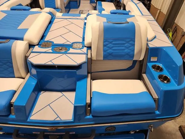 Slide: The Image of 2023 Malibu 26 LSV boat interior with blue and white seating and cup holders. - 49