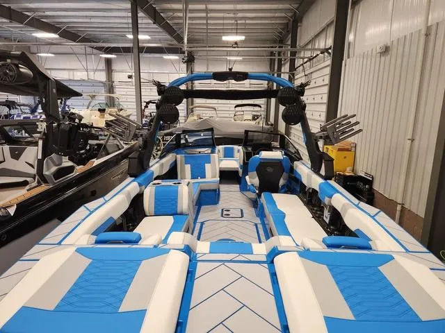 Slide: The Image of 2023 Malibu 26 LSV boat with blue and white interior in a showroom. - 6