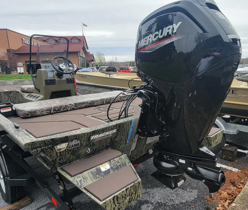 Slide: The Image of 2025 Tracker Grizzly 1860 CC boat with Mercury engine, parked outdoors. - 5