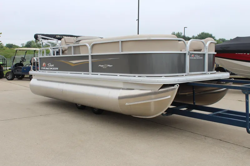 Slide: The Image of 2025 Sun Tracker Party Barge 18 DLX pontoon boat on trailer, parked outdoors. - 5