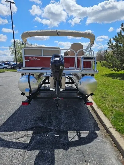 Slide: The Image of 2025 Sun Tracker Bass Buggy 16 XL Select pontoon boat on trailer, parked outdoors. - 3