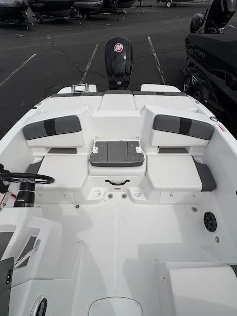 Slide: The Image of 2025 Tahoe T18 boat interior with seating and motor, parked in a lot. - 2