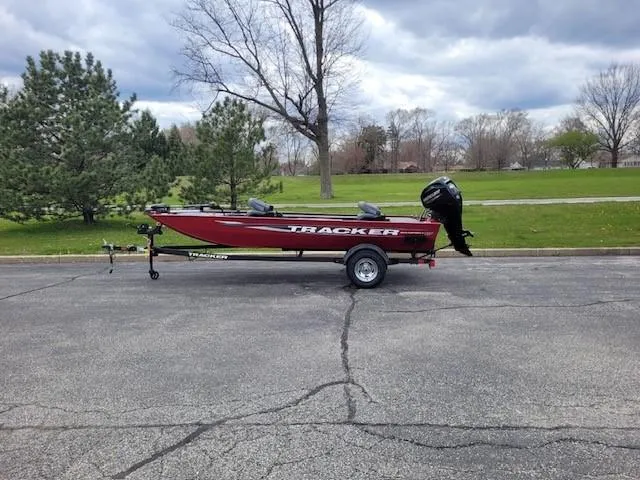 The Image of 2025 Tracker Panfish 17 boat on trailer, parked outdoors with trees in the background. - 0