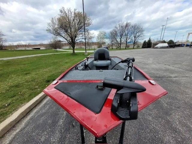 Slide: The Image of 2025 Tracker Panfish 17 boat with red trim, parked on pavement near grassy area. - 3