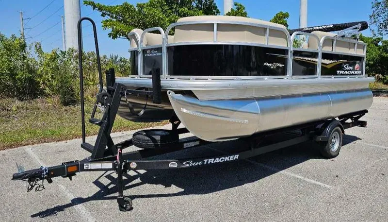 Slide: The Image of 2025 Sun Tracker Party Barge 16 DLX pontoon boat on trailer in parking lot. - 3