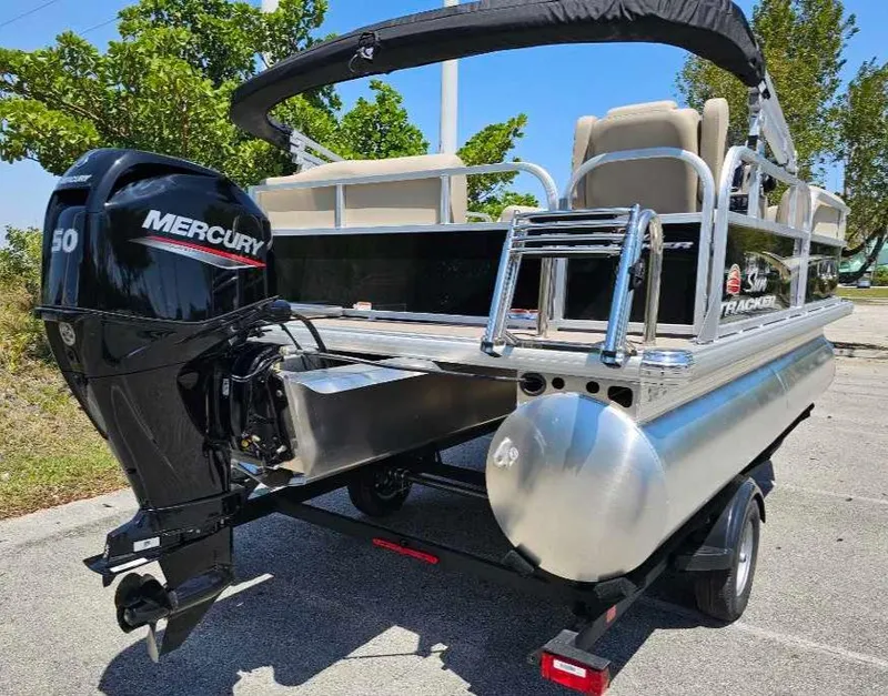 Slide: The Image of 2025 Sun Tracker Party Barge 16 DLX pontoon boat with Mercury 50 engine, parked outdoors. - 7