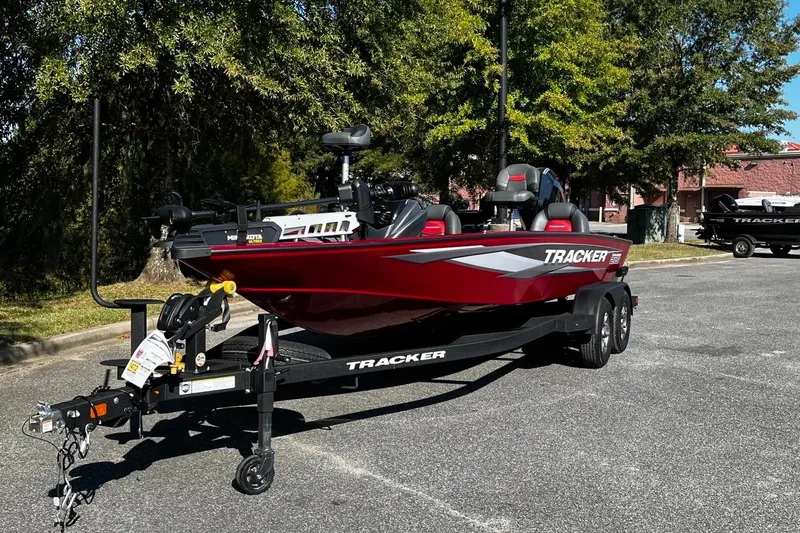 The Image of 2025 Tracker Savage 215 boat on trailer, parked outdoors, with trees in the background. - 2