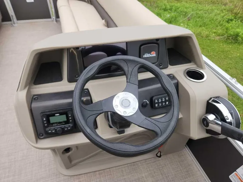Slide: The Image of 2025 Sun Tracker Party Barge 18 DLX steering console with controls and cup holder. - 4