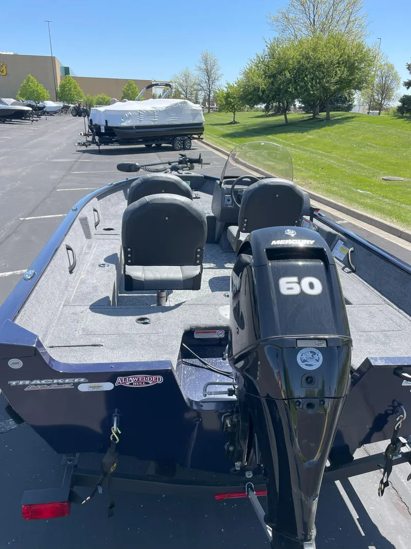 Slide: The Image of 2025 Tracker Pro Guide V-16 SC boat with 60 HP engine in parking lot. - 2
