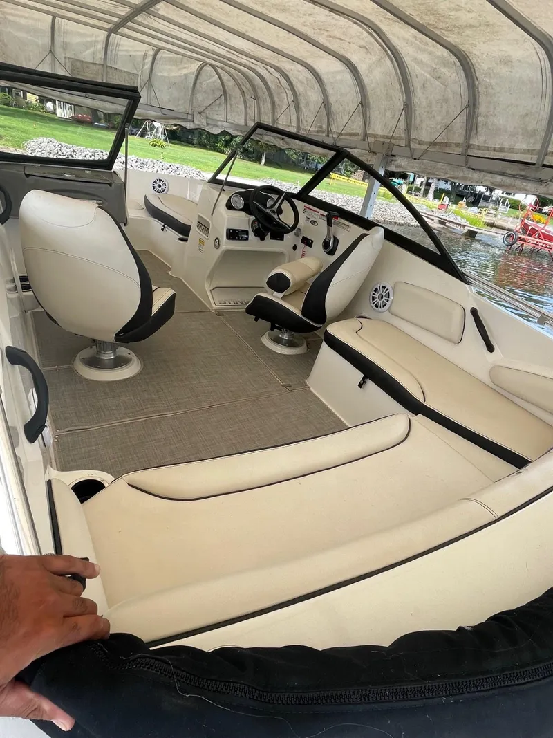 Slide: The Image of 2022 Stingray 191 DC boat interior with white seating and modern dashboard under canopy. - 5