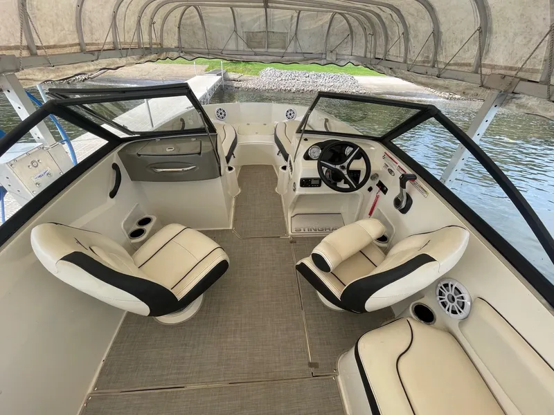 Slide: The Image of 2022 Stingray 191 DC boat interior with beige seating, steering wheel, and canopy. - 6
