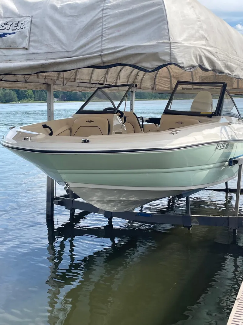 Slide: The Image of 2022 Stingray 191 DC boat docked on a lake under a canopy. - 8