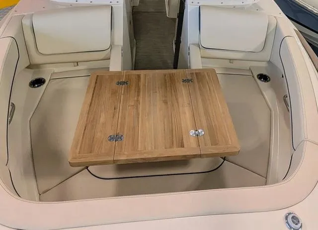 Slide: The Image of 2023 Chris-Craft Calypso 24 interior with wooden table and beige seating. - 12