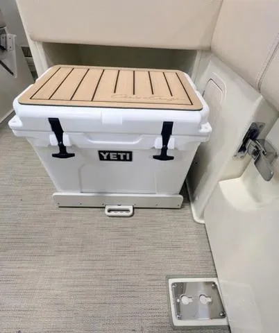 Slide: The Image of YETI cooler on 2023 Chris-Craft Calypso 24 boat, beige interior, secured with straps. - 32
