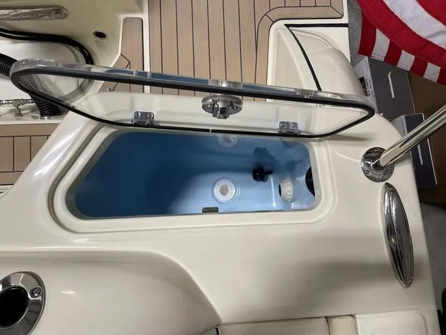 Slide: The Image of 2023 Chris-Craft Calypso 24 boat storage compartment with open lid, featuring teak flooring. - 38