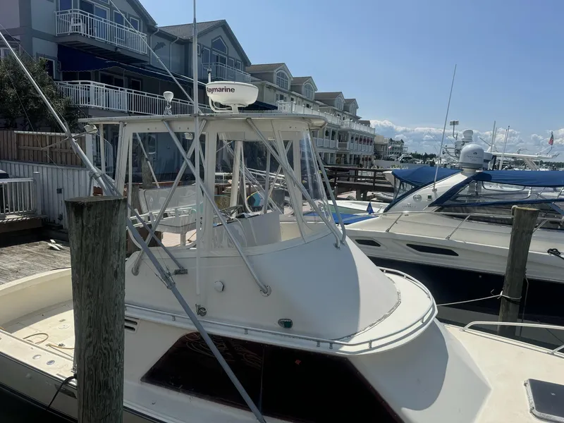 Slide: The Image of 1985 Blackfin 32 Flybridge boat docked at a marina, surrounded by waterfront homes. - 3