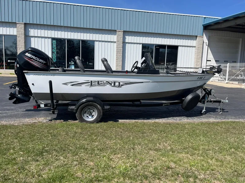 Slide: The Image of 2017 Lund 1750 Rebel XS SS boat with Mercury engine, parked outside a building. - 0