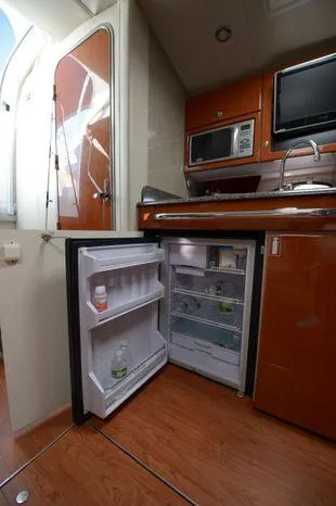 Slide: The Image of 2007 Formula 34 PC yacht interior with open fridge, microwave, and wooden cabinetry. - 28