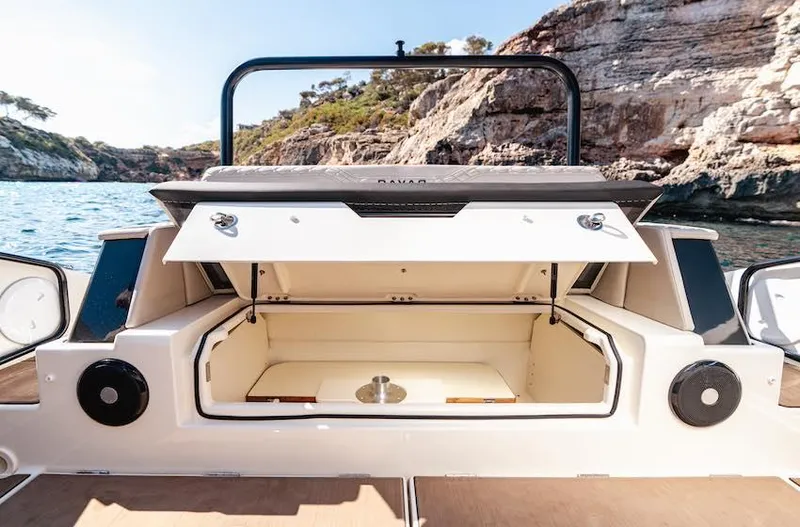 Slide: The Image of 2025 Navan S30 boat storage compartment open, showcasing spacious interior against scenic rocky coastline. - 6
