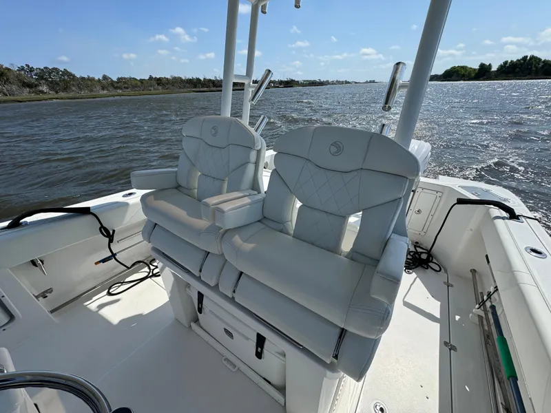 Slide: The Image of 2022 Edgewater 280CC boat interior with dual seats, on a sunny day by the water. - 15