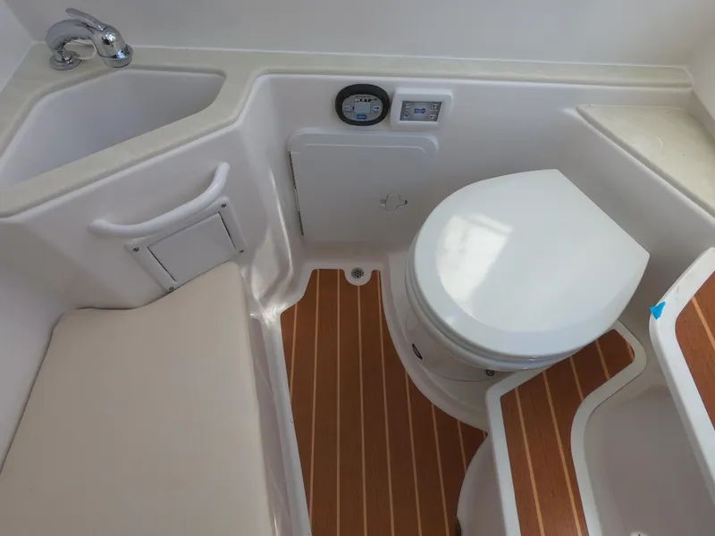 Slide: The Image of 2022 Edgewater 280CC boat bathroom with sink, toilet, and wood-patterned flooring. - 25