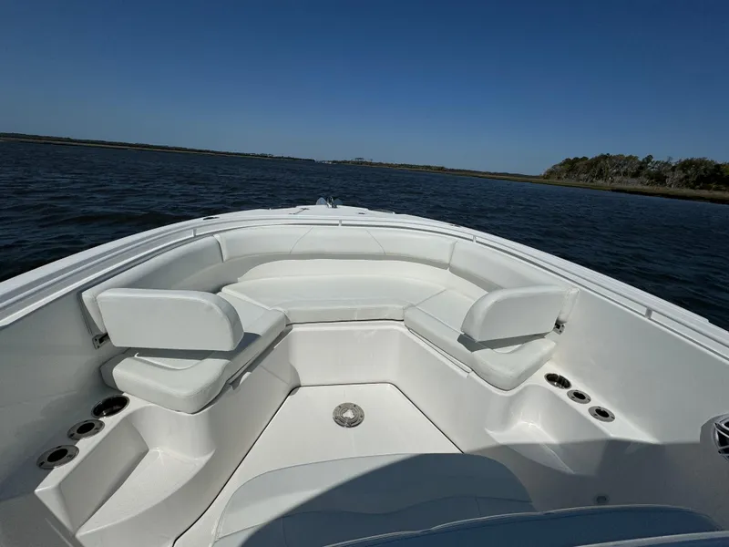 Slide: The Image of 2022 Edgewater 280CC boat interior with white seating, on calm water. - 30